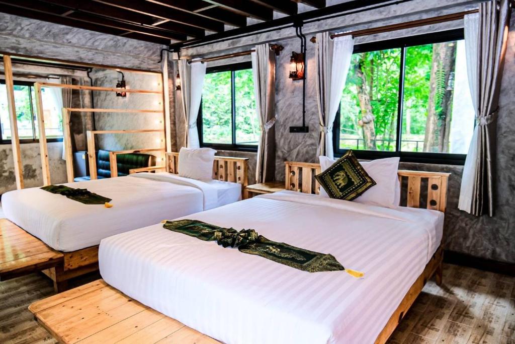 two beds in a room with two windows at คีรีเขาสกริเวอร์ Keereekhaosokriver in Khao Sok National Park