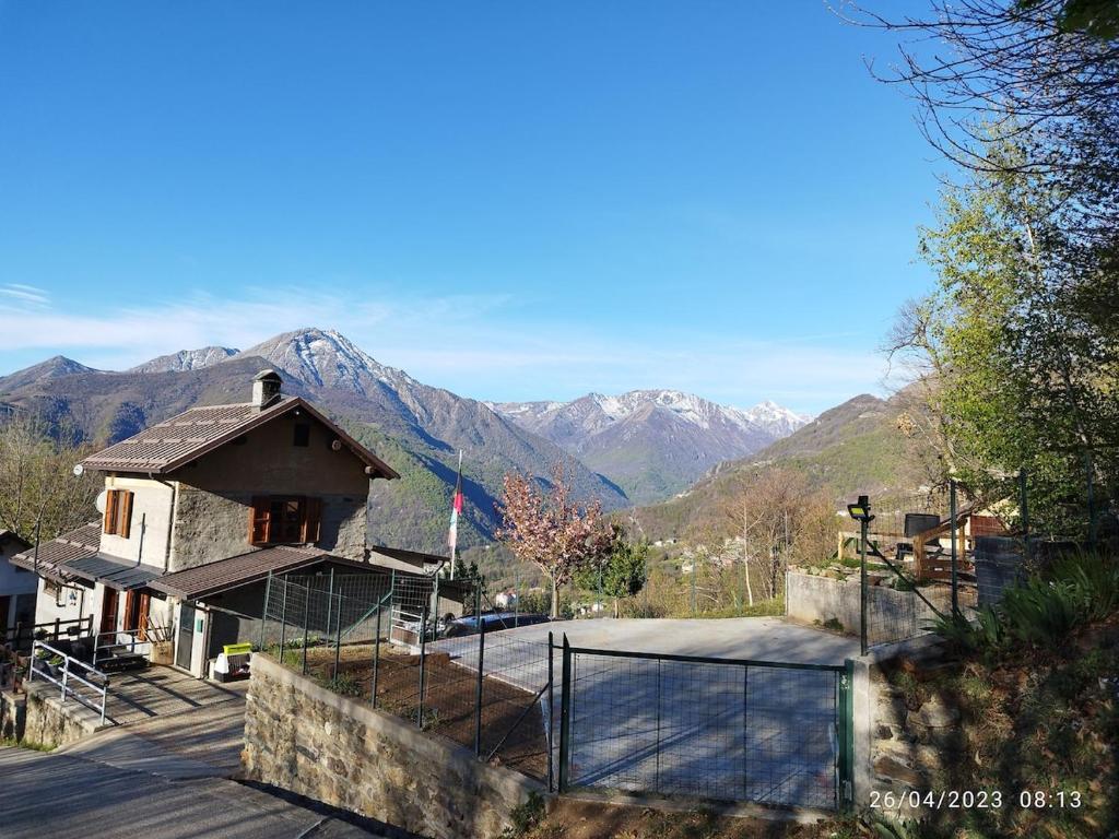 a house with a fence and mountains in the background at Casa Pinocchio in Viù