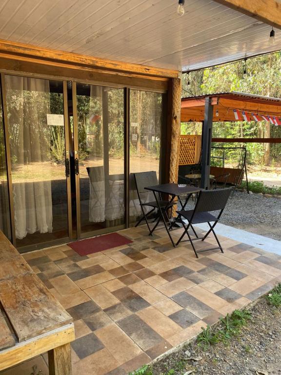 a screened in patio with a table and chairs at Las palmeras de Colbún in Colbún