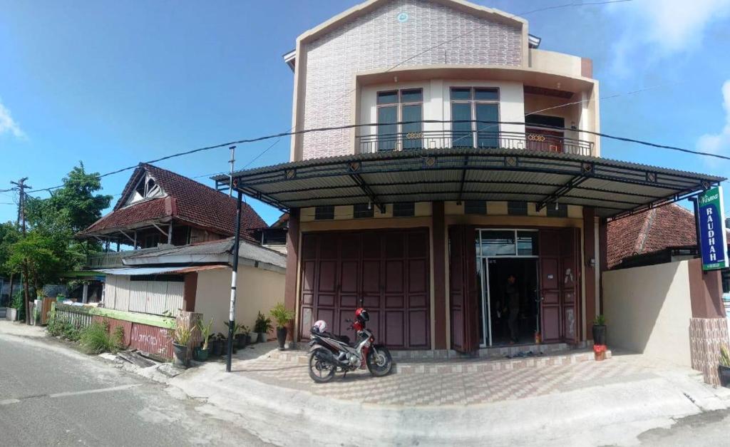a motorcycle parked in front of a house with a balcony at Wisma Raudah Wakatobi in Mandati