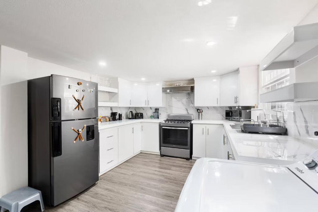 eine Küche mit weißen Schränken und einem Edelstahlkühlschrank in der Unterkunft 2 Bedroom - 1 Bath Condo - 2 min walk to beach in Bridgetown