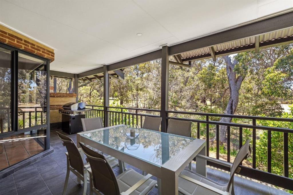ein Esszimmer mit einem Glastisch und Stühlen auf einem Balkon in der Unterkunft Acorn Delight - Tranquil Retreat by the Golf Course in Dunsborough