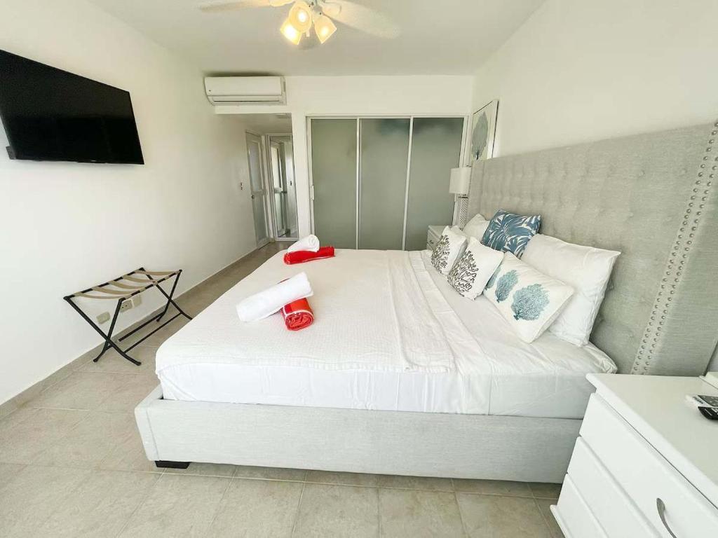 ein Schlafzimmer mit einem großen weißen Bett und Kissen in der Unterkunft Oasis by the beach Retiro 1 in Punta Cana