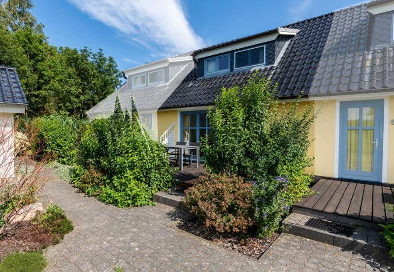 ein gelbes Haus mit einer Holzterrasse im Hof in der Unterkunft Ferienhaus für 3 Personen   2 Kinder ca 60 m in Neuenkirchen, Ostseeküste Deutschland Rügen - a87291 in Neuenkirchen