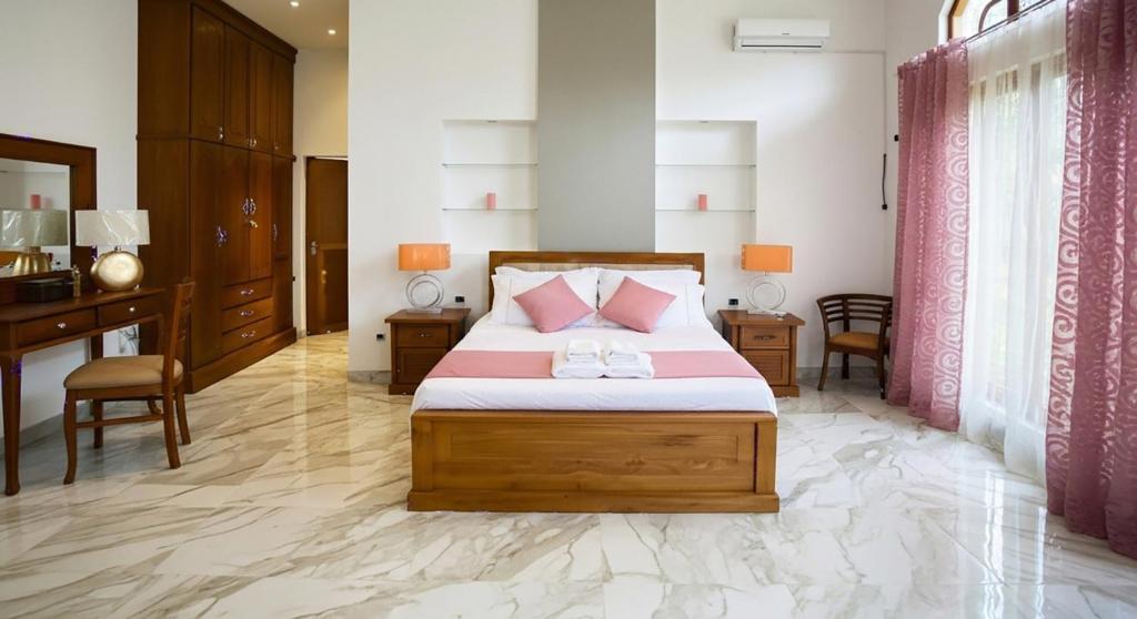 a bedroom with a bed with pink pillows and a desk at Silva Villa Negombo in Negombo
