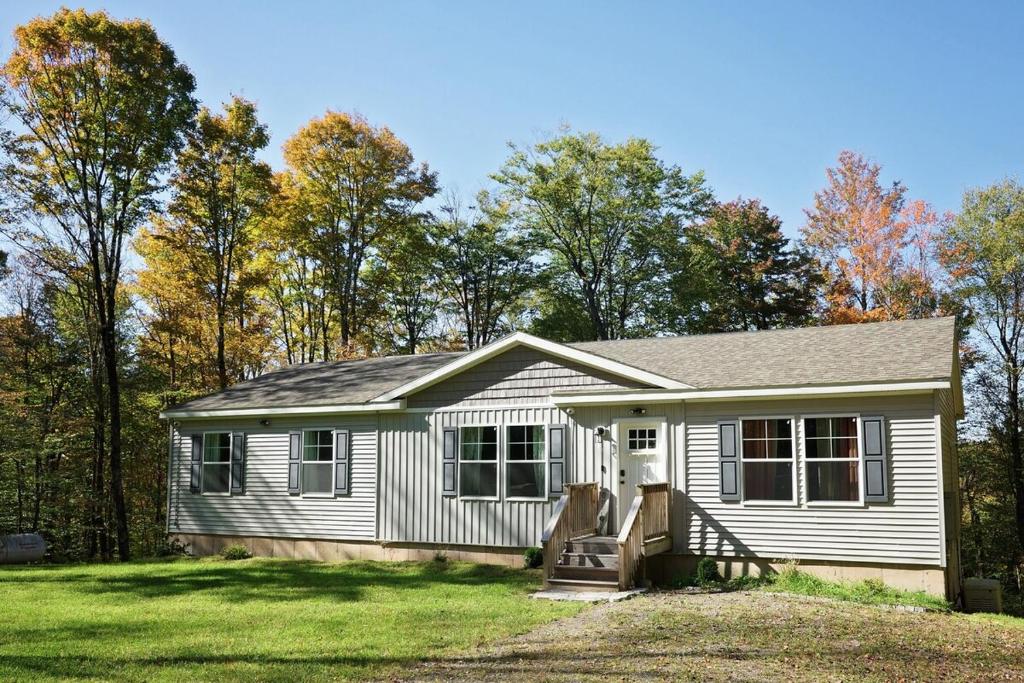 una pequeña casa blanca con árboles en el fondo en Oneonta Hideaway, en Oneonta