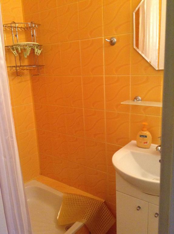 an orange bathroom with a shower and a sink at u sylwana in Kuźnica