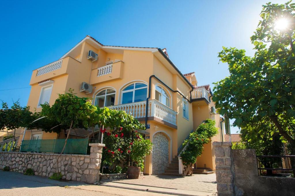 une maison jaune avec une clôture et des arbres dans l'établissement Familienpension Tina Appartement 7, à Šilo