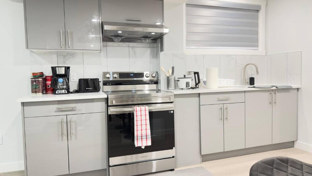 a kitchen with white cabinets and a stove top oven at Zillion’s Bliss - Basement Suite in Calgary