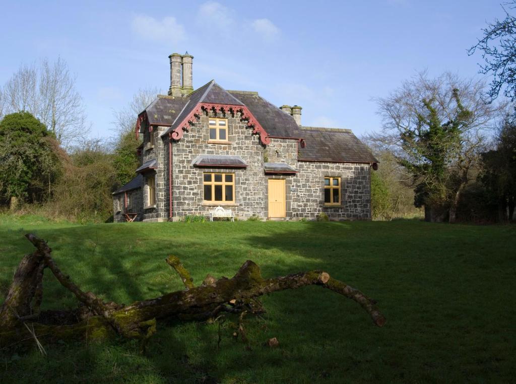 an old stone house on a grassy field at Ballealy Cottage in Randalstown