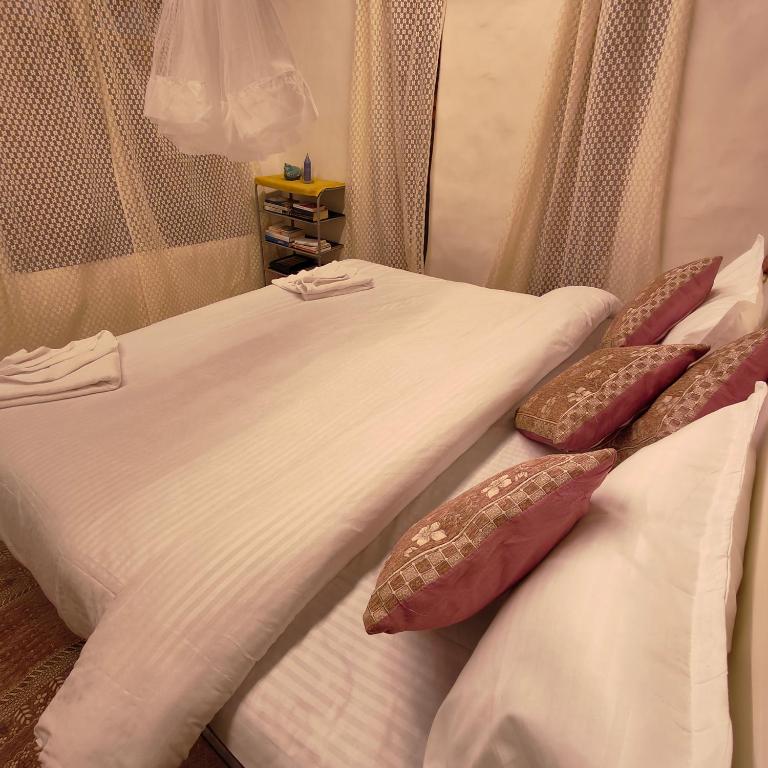 two beds in a hotel room with white sheets and pillows at Khoj Cottage & Cafe in Dharmsāla