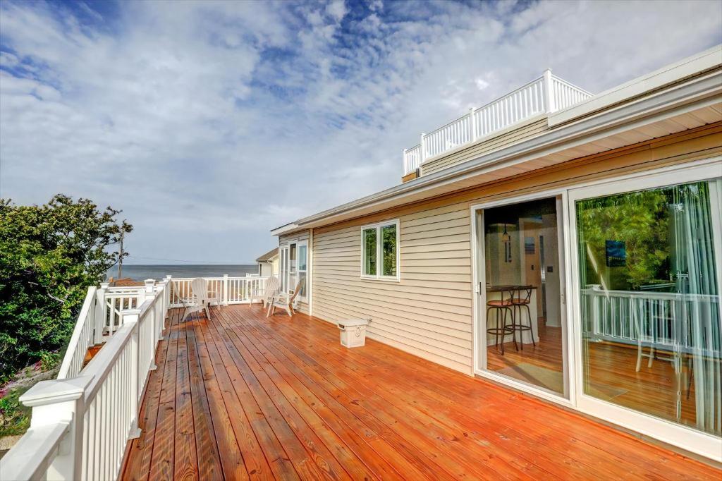 une maison avec une terrasse en bois à côté de l'océan dans l'établissement Sunset Retreat, à North Cape May