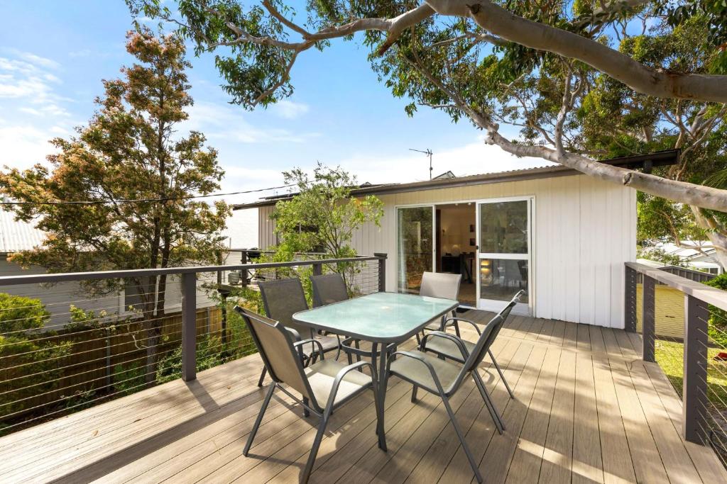 Un patio con una mesa y sillas en una terraza. en Sandpiper at Jervis Bay - Rustic Retreat, en Callala Beach