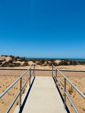 a walkway to the beach with a blue sky at Summer Port Lodge in Port Hedland