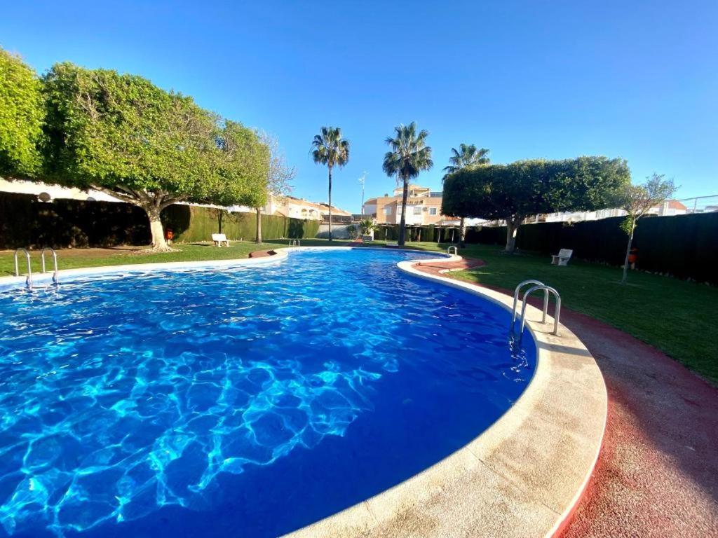 a large pool with blue water in a yard at Bungalow Brisa de Mar in Torrevieja