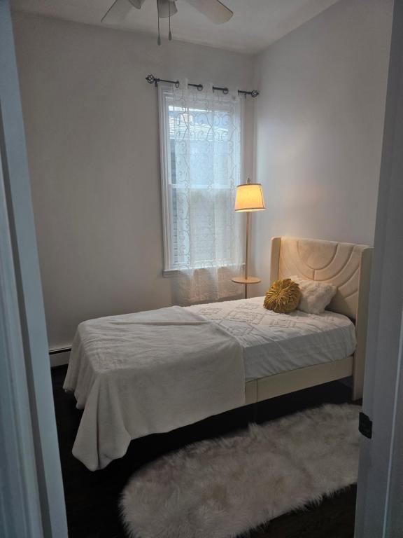 ein Schlafzimmer mit einem Bett mit einer Lampe und einem Fenster in der Unterkunft Cozy Getaway 3-Prudential Center, NJPAC, Penn Station in Kearny