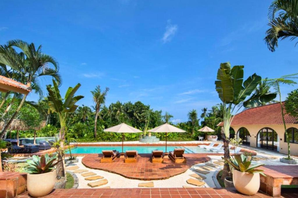 a pool at a resort with chairs and umbrellas at Neona Spacious 4 BR Private Pool Villa ZN364 in Tanah Lot