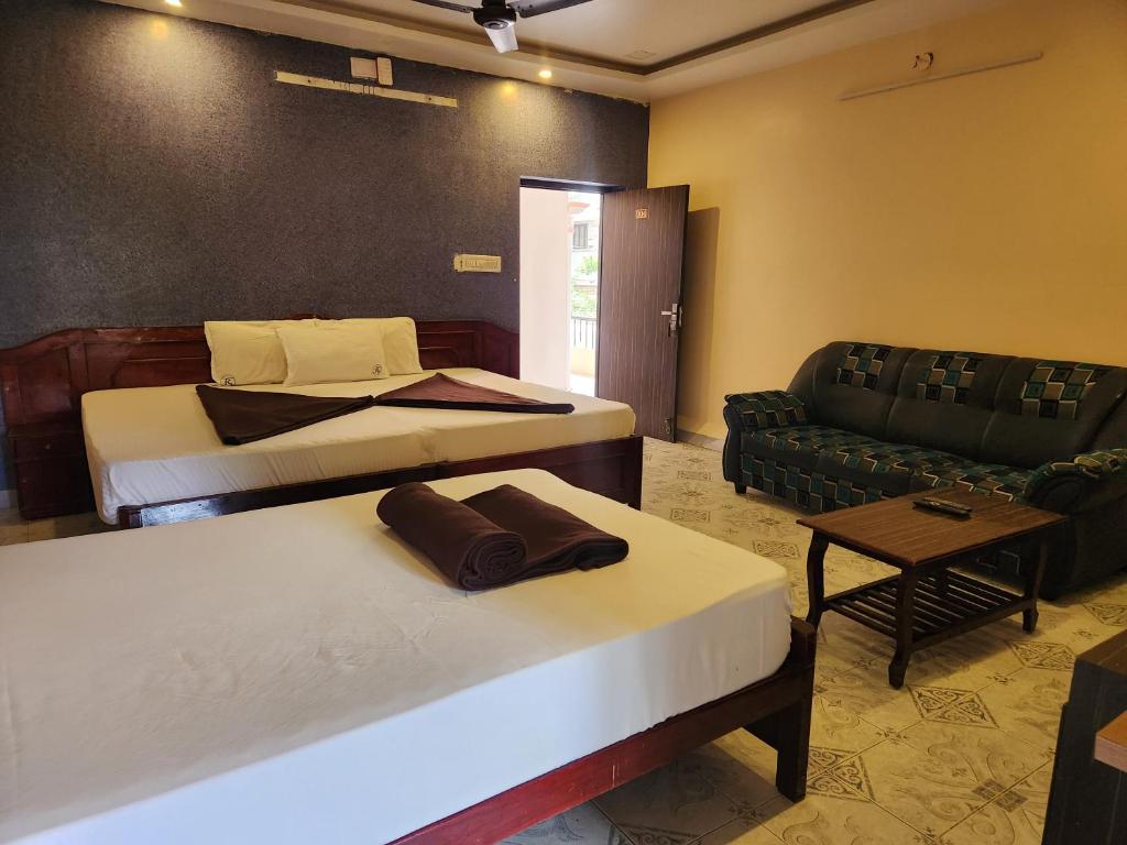 una habitación de hotel con dos camas y un sofá en SKT's Wisteria Inn, en Yercaud