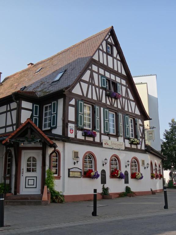 un bâtiment à colombages avec des fenêtres vertes à volets dans l'établissement Hotel Schützenhof mit Wellness, à Bürstadt