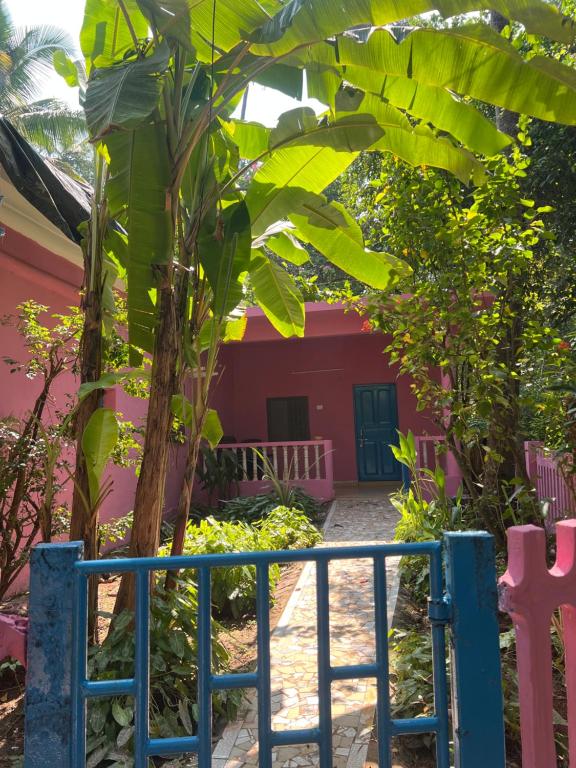 une clôture devant une maison rouge avec un bananier dans l'établissement The Maze House Anjuna!, à Anjuna