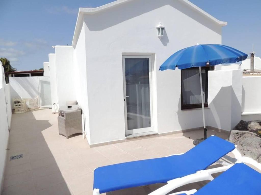 a blue umbrella and chairs on a patio at Ferienwohnung Luna in Charco del Palo