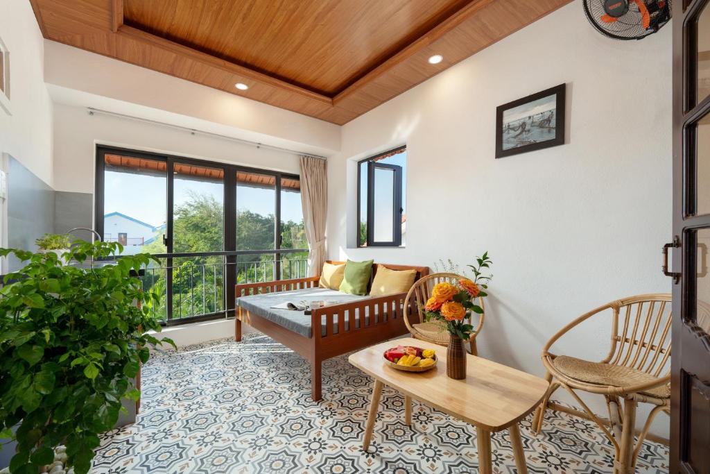 un salon avec un canapé et une table dans l'établissement Red Flower Cottages Homestay, à Hội An