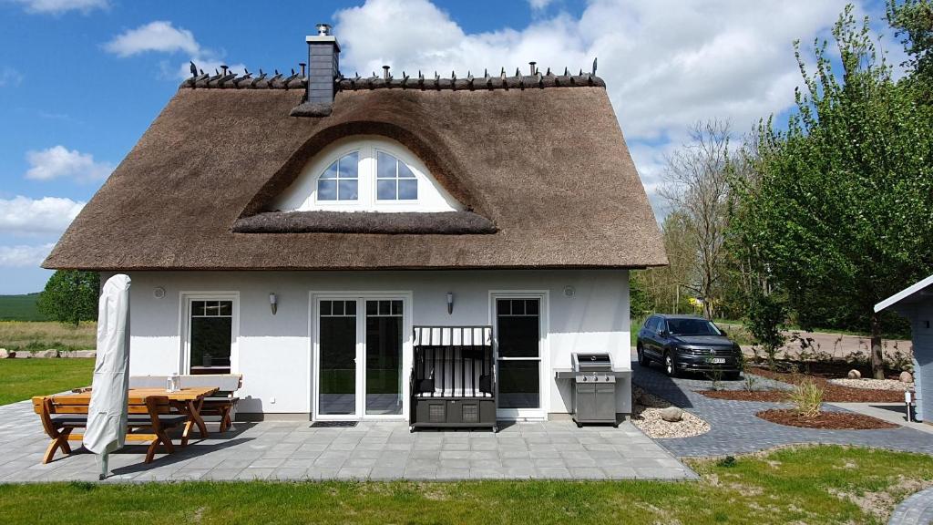 a small house with a thatched roof with a table and a grill at Ferienhaus In Mellnitz Mit Großem Garten in Poseritz