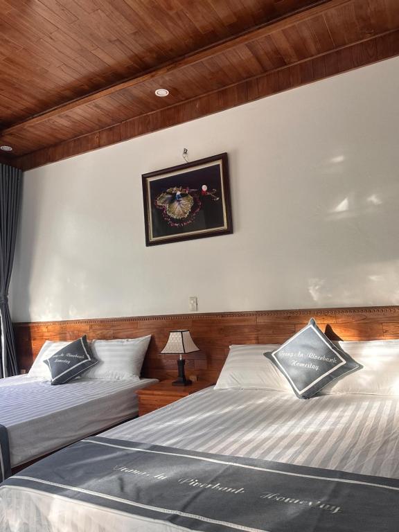 a bedroom with two beds and a picture on the wall at Tràng An Riverbank Homestay in Nguyên Ngoại