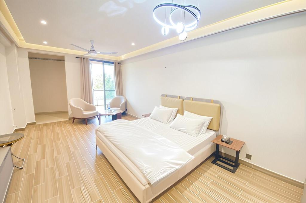 a bedroom with a large white bed and a table at Luxury Studio at Monal Murree with Mountain Views in Murree