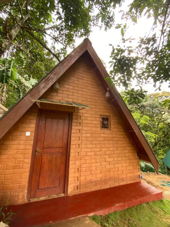 a small brick building with a wooden door at Green Forrest Cabanas - Ella in Ella