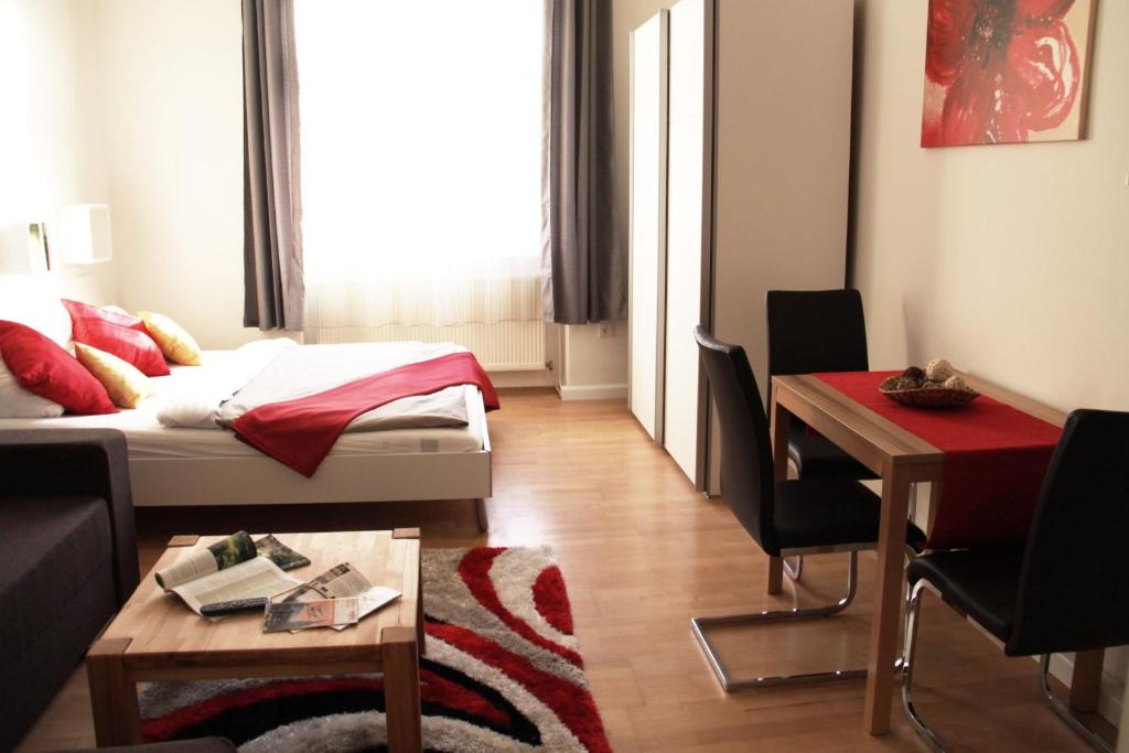 ein Wohnzimmer mit einem Bett, einem Tisch und einem Schreibtisch in der Unterkunft Apartment Inzersdorferstraße in Wien