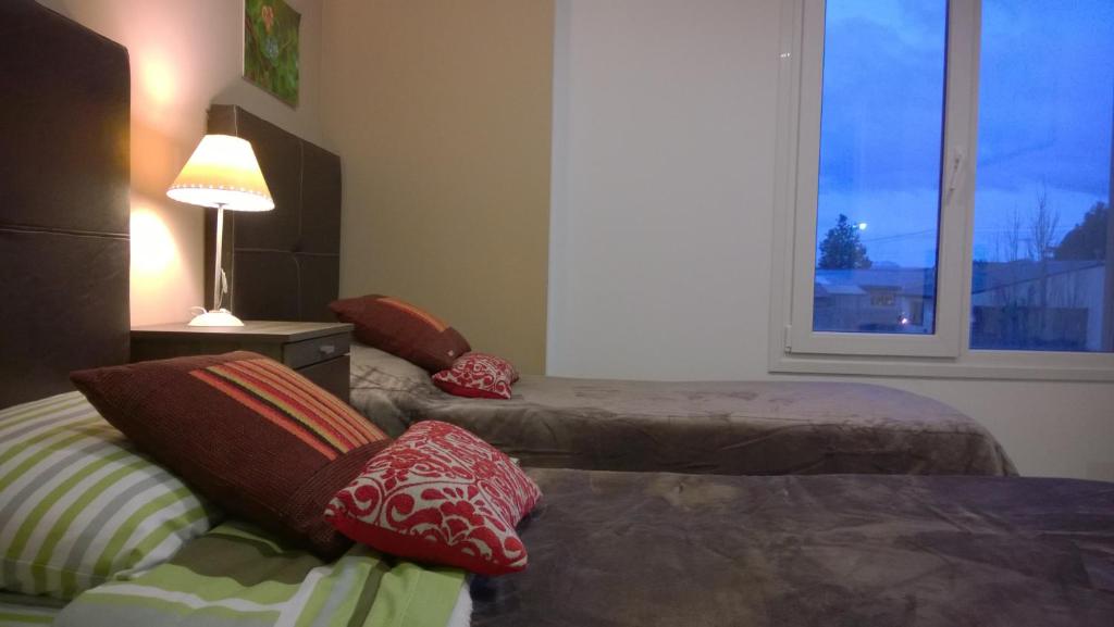 ウシュアイアにあるMagallanesのベッド2台、ランプ、窓が備わる客室です。