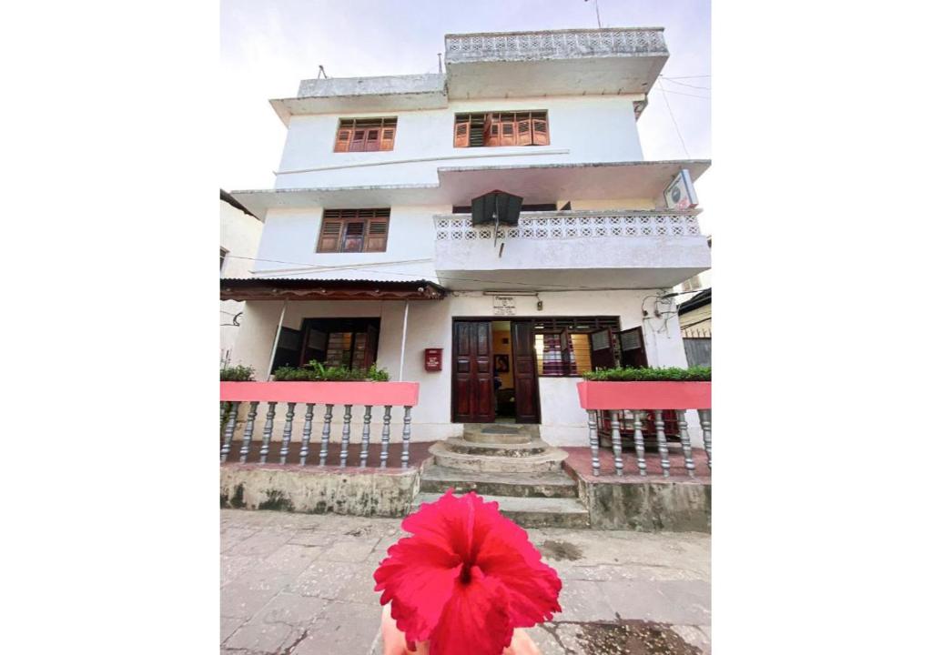 a person with a red umbrella in front of a building at Flamingo Guest House in Zanzibar City