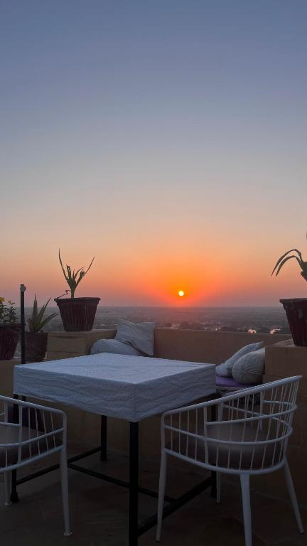a table and two chairs on a balcony with a sunset at Hotel Surja Jaisalmer in Jaisalmer