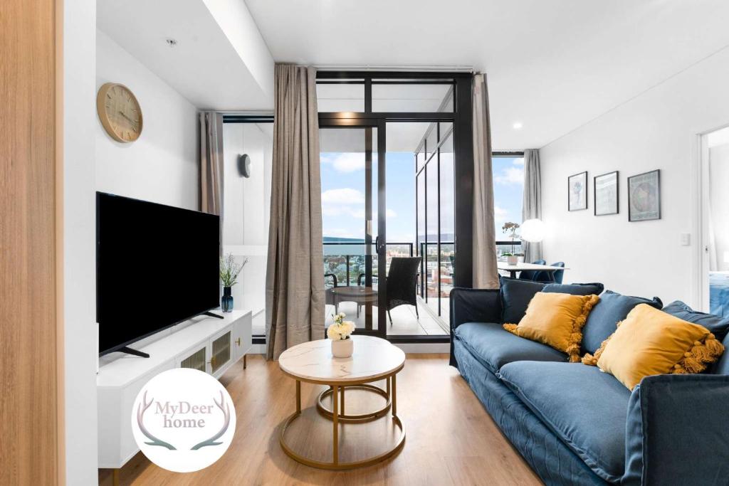 a living room with a blue couch and a tv at The elegant 1BR CBD Apt - City view - Parking in Adelaide