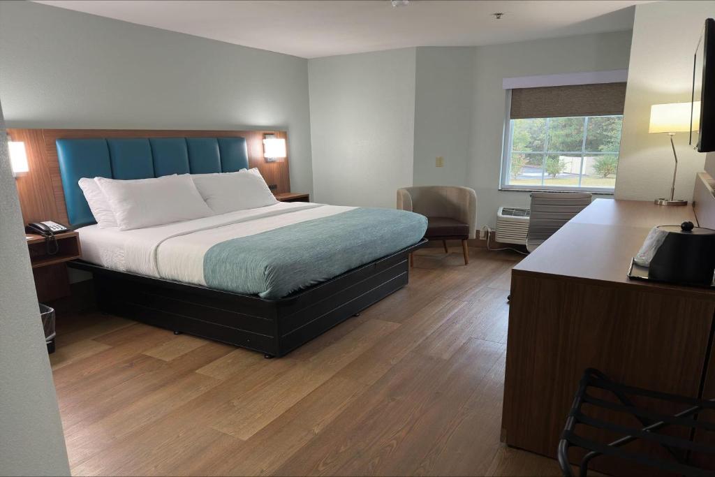 a bedroom with a bed with a blue headboard and a desk at Wingate by Wyndham Macon I-475 in Macon