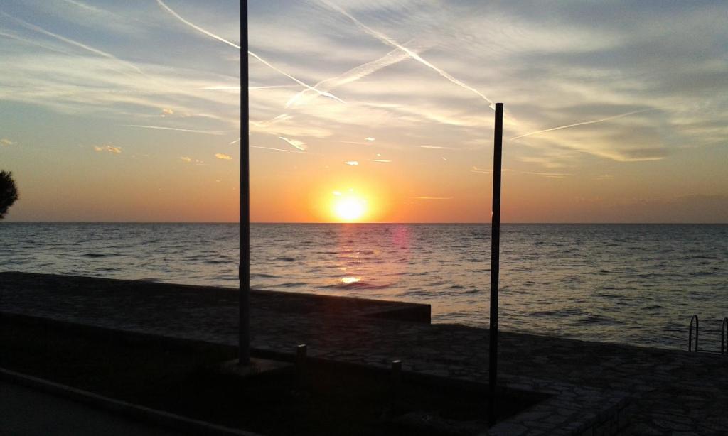 a sunset over the ocean with two poles at Apartments Elda in Poreč