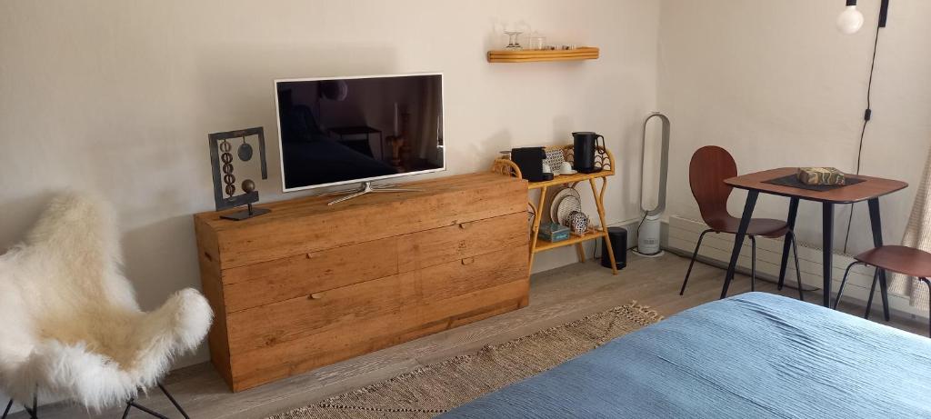 Una sala de estar con un televisor sobre una cómoda de madera. en Au Bourg, en Le Landeron
