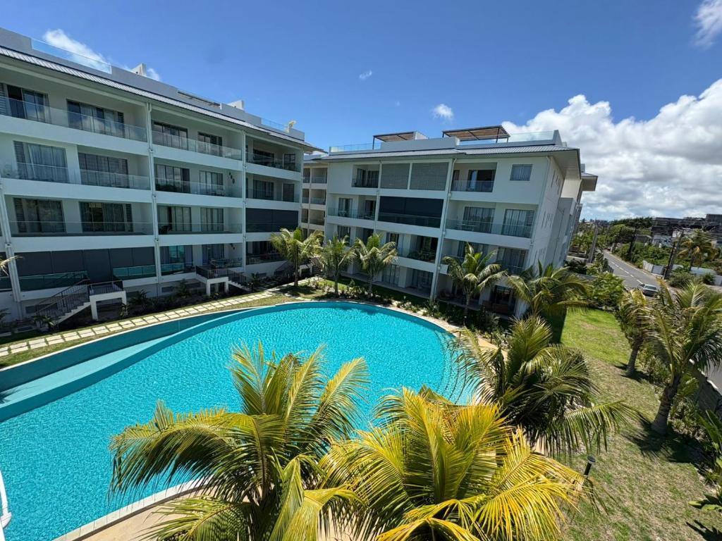 Ki Resort by LOV Mauritius في غراند بايَ: مبنى سكني مع حمام سباحة وأشجار النخيل