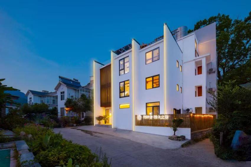 ein großes weißes Haus mit vielen Fenstern in der Unterkunft Huazhu Luxury Huangshan Warm Wood Homestay Tangkou Nandamen Branch in Tangkou