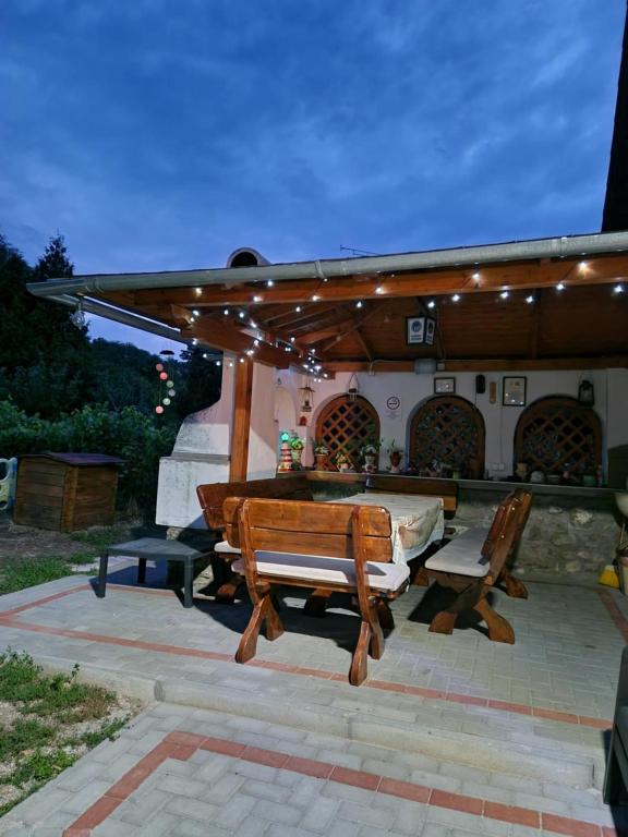 a patio with two wooden benches under a pergola at Nosztalgia Nyaralóház in Szigliget
