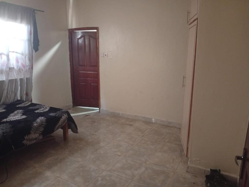 Schlafzimmer mit einem Bett und einer Holztür in der Unterkunft Kings Court in Kitengela 