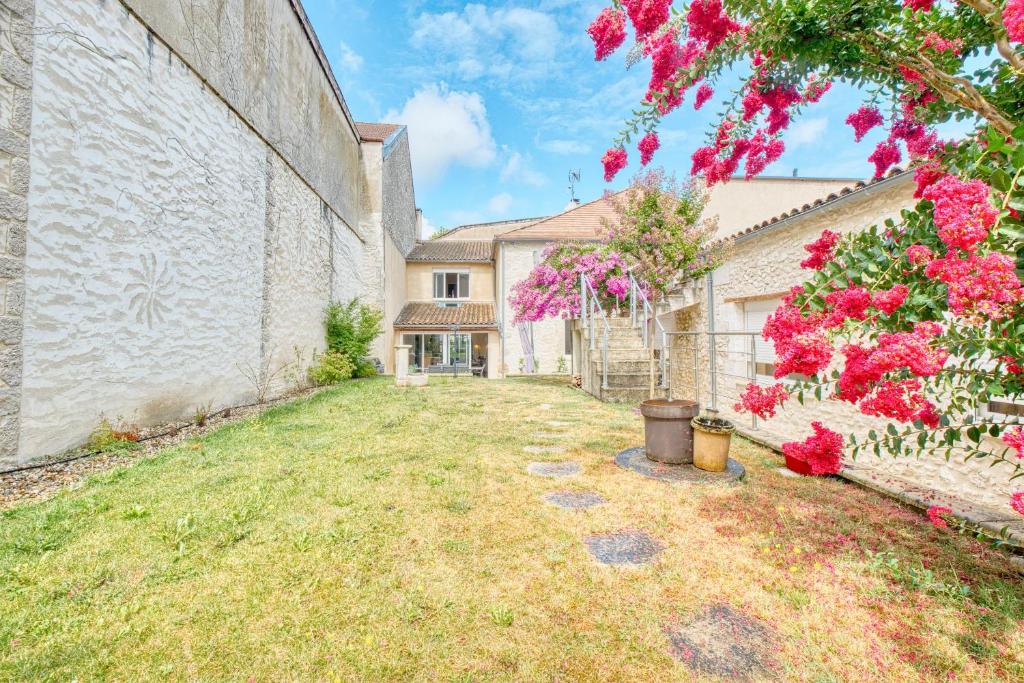 an empty yard in front of a building with pink flowers at L'envie Eymet in Eymet