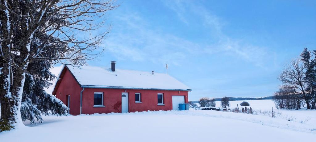 a red barn with snow on it in a field at Maison plain-pied Calme et Nature in Cuvier