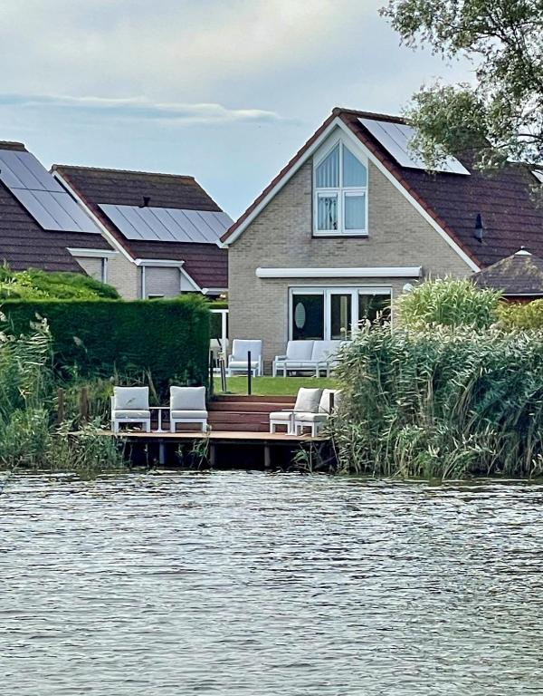 a house on a dock on a body of water at Design Idyll am Wasser in Breskens Haus mit Steg, Lounge, E Ladestation inklusive, 3 Schlafzimmer und 2 WCs in Breskens