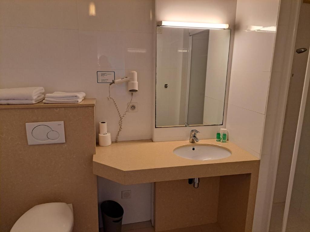a bathroom with a sink and a toilet and a mirror at Hôtel Le Collier in Antibes