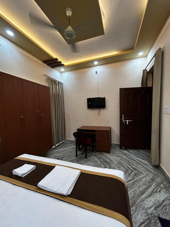 a bedroom with a bed and a desk and a tv at Shri Homes in Varanasi