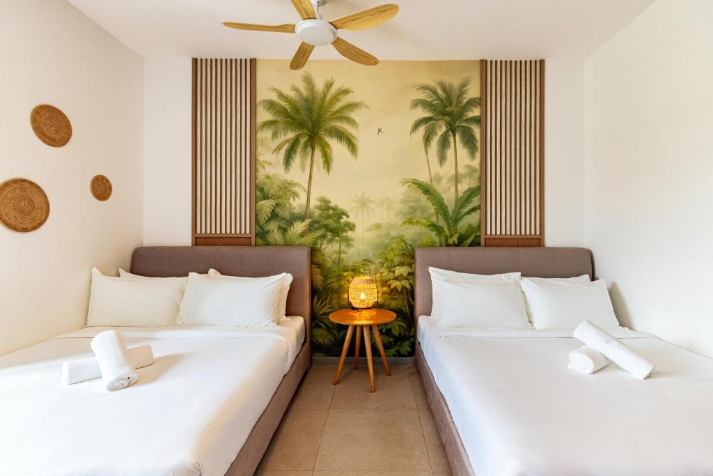 - 2 lits dans une chambre avec des palmiers dans l'établissement 22 Macalisterz Premium Suites Penang by Byon, à George Town
