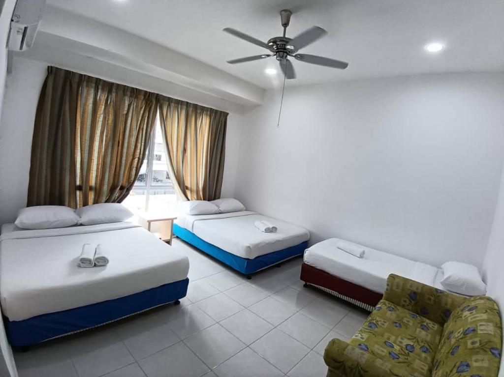 a hotel room with two beds and a ceiling fan at Raub Sutera Homestay in Kampong Sempalit Ulu