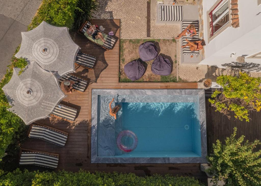 eine Draufsicht auf einen Pool mit Stühlen und Sonnenschirmen in der Unterkunft The Salty Surf & Yoga in Monte Estoril